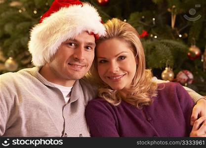 Couple Relaxing In Front Of Christmas Tree