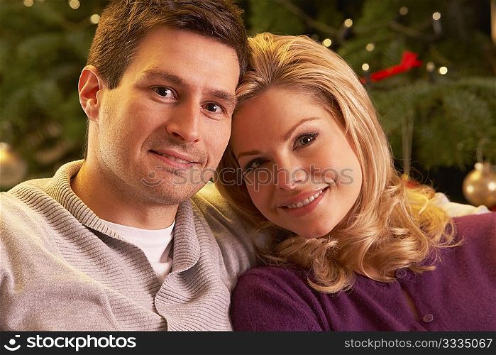 Couple Relaxing In Front Of Christmas Tree