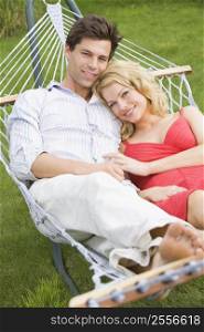 Couple relaxing in hammock smiling