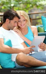 Couple relaxing in sofa with electronic tablet
