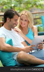 Couple relaxing in sofa with electronic tablet