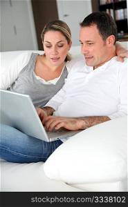 Couple relaxing in sofa with laptop computer