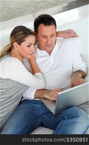 Couple relaxing in sofa with laptop computer
