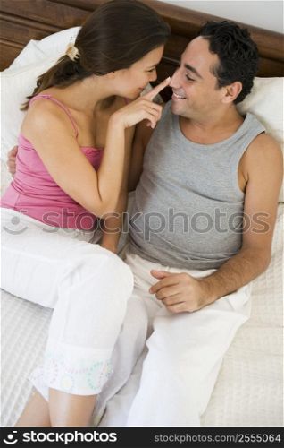 Couple relaxing on bed in bedroom bonding and smiling (selective focus)