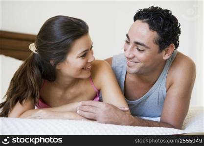 Couple relaxing on bed in bedroom smiling (selective focus)