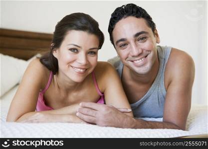 Couple relaxing on bed in bedroom smiling (selective focus)
