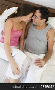 Couple relaxing on bed in bedroom snuggling and smiling (selective focus)