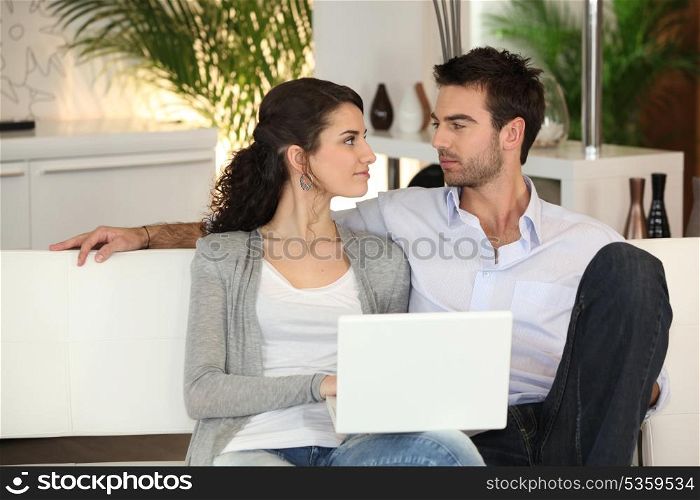 Couple relaxing on sofa with computer