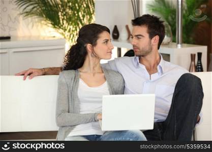 Couple relaxing on sofa with computer