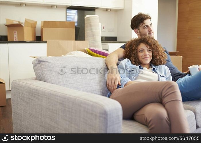 Couple Relaxing On Sofa With Hot Drink In New Home
