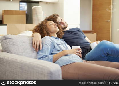 Couple Relaxing On Sofa With Hot Drink In New Home