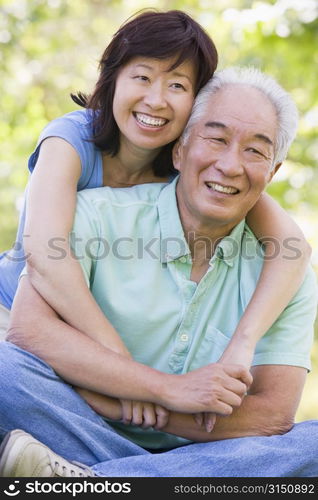 Couple relaxing outdoors in park smiling