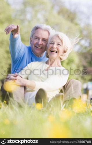 Couple relaxing outdoors pointing and smiling
