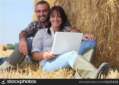 Couple relaxing with laptop in straw