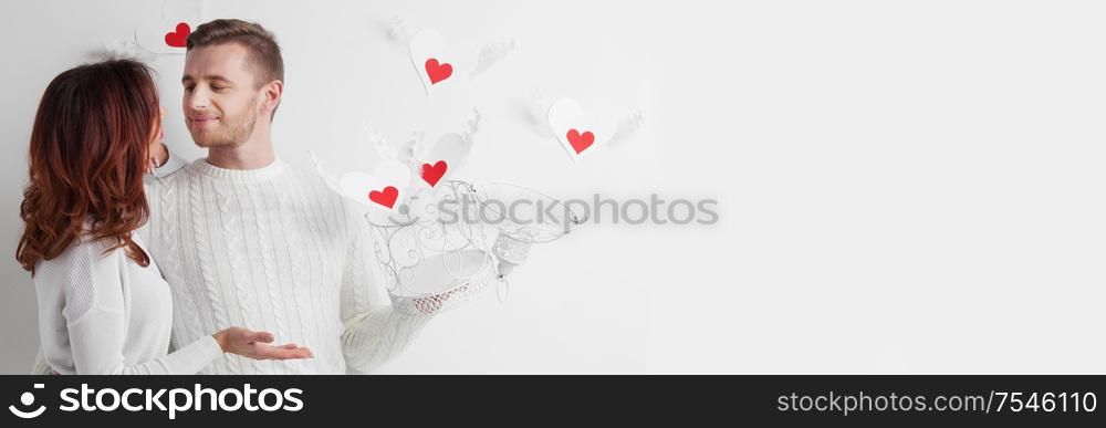 Couple releasing love concept, man and woman open cage with winged hearts, valentines day white and red colors. Couple in love with winged hearts
