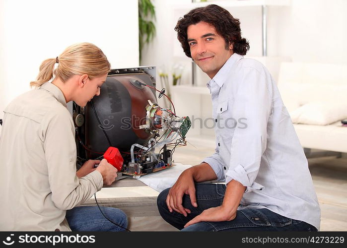 Couple repairing broken television