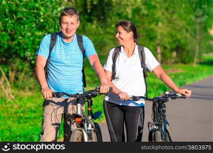 couple riding a bicycle in a park in the morning