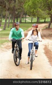Couple riding bicycle in park