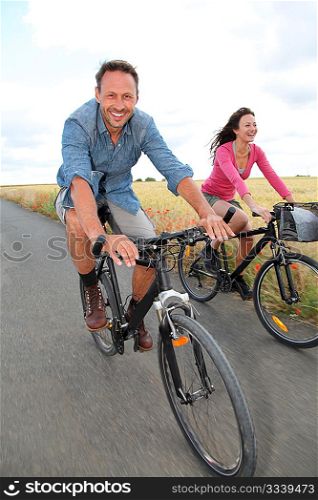 Couple riding bicycle on country road