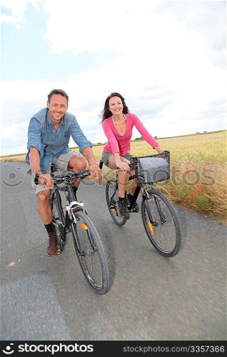 Couple riding bicycle on country road