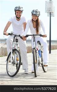 couple riding bicycle wearing cycle helmet
