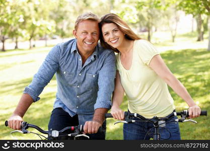 Couple riding bikes in park