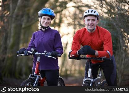 Couple Riding Mountain Bikes Through Woodlands