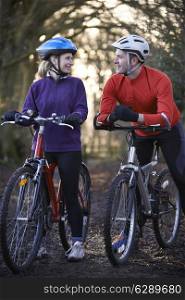 Couple Riding Mountain Bikes Through Woodlands