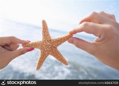 Couple&rsquo;s hands holding starfish at the beach