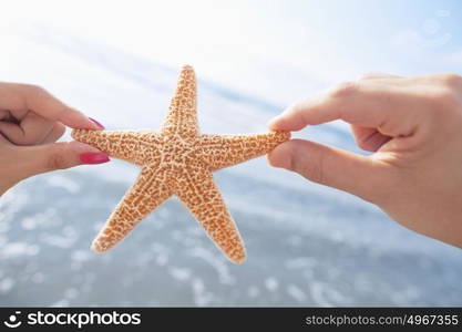 Couple&rsquo;s hands holding starfish at the beach