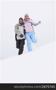Couple running down snow-covered hill low angle view