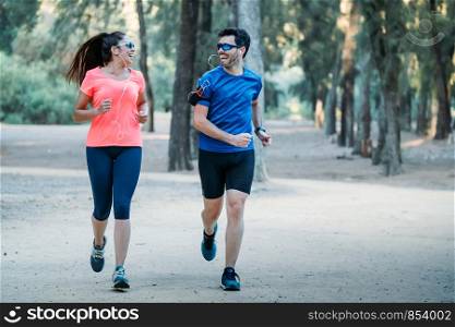 couple running in a park looking at each other and smiling as they listen to music