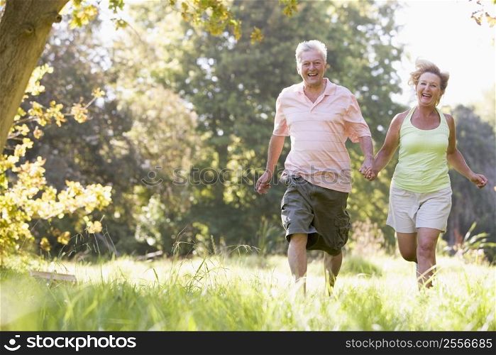 Couple running in park holding hands and smiling