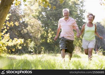 Couple running in park holding hands and smiling