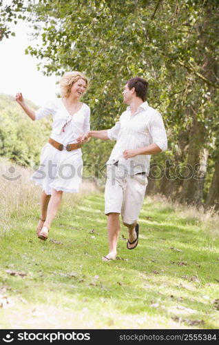 Couple running on path holding hands and smiling