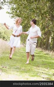 Couple running on path holding hands and smiling