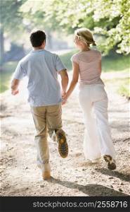Couple running outdoors holding hands