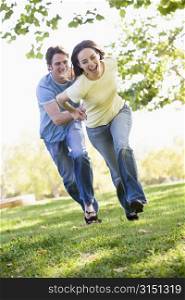 Couple running outdoors holding hands and smiling
