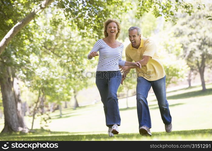 Couple running outdoors in park and smiling