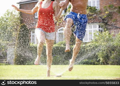 Couple Running Through Garden Sprinkler