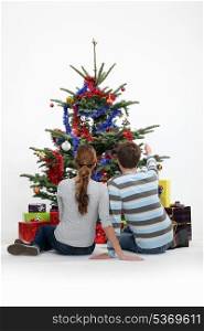 Couple sat by Christmas tree