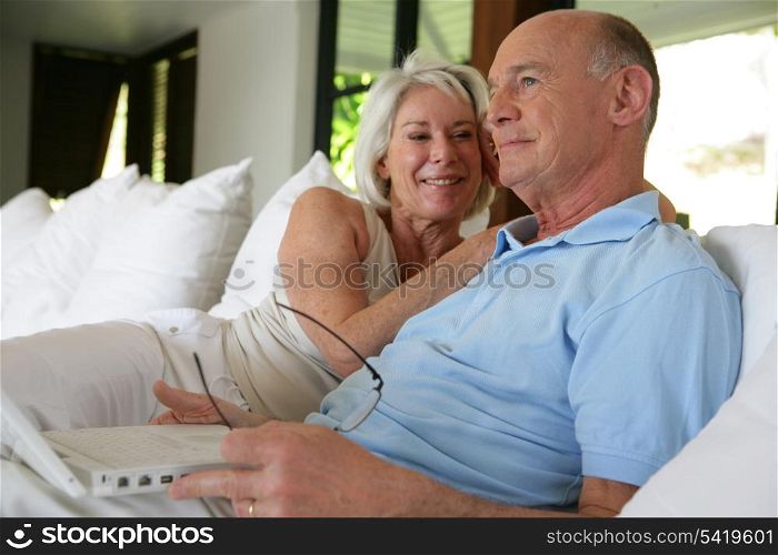 Couple sat on their veranda with laptop
