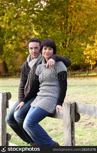 Couple sat on wooden fence