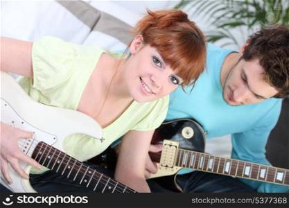 Couple sat playing the electric guitar
