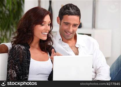 Couple sat with laptop on couch
