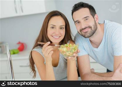 Couple sharing a salad in the kitchen