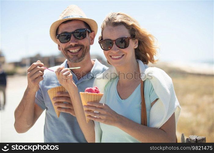 couple sharing ice cream while enjoying sunny weather outdoors
