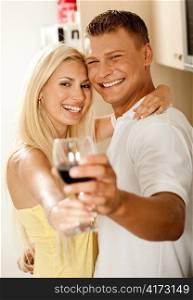 Couple sharing wine glass and smiling as they look into the camera
