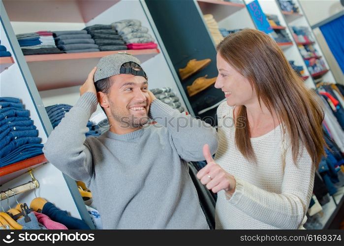 Couple shopping, man trying on hat