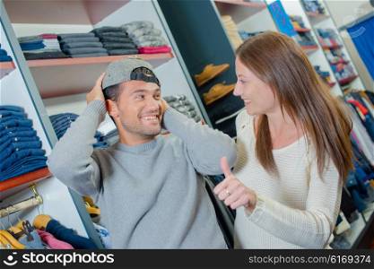 Couple shopping, man trying on hat